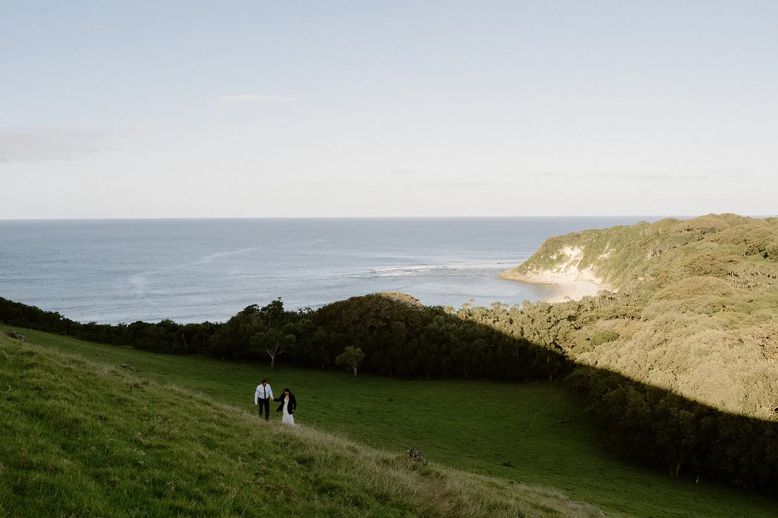Mel and Brent walking a green ridge above the surf, Lord Howe Island