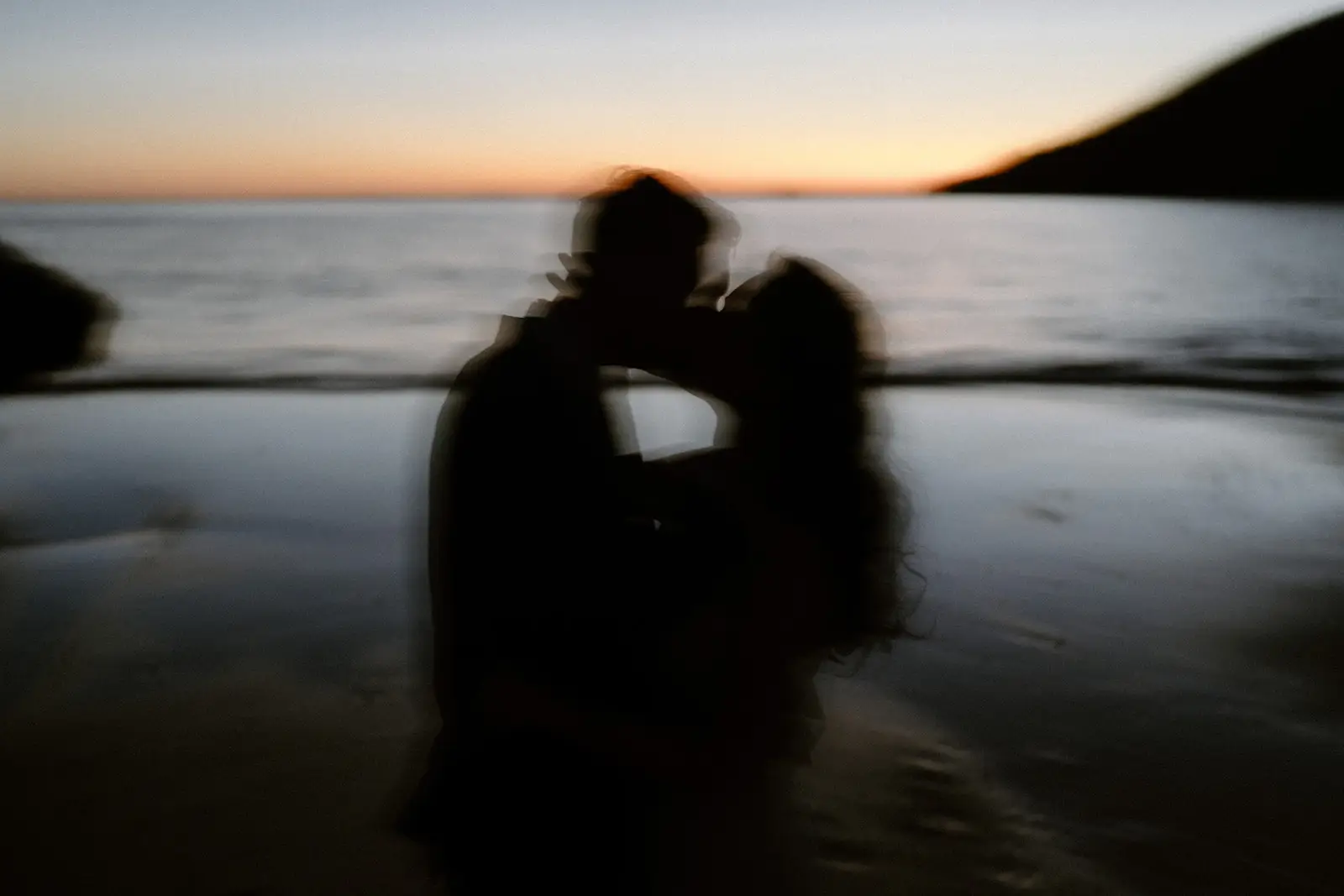 Mel and Brent embracing on the wet sand at sunset, Lord Howe Island