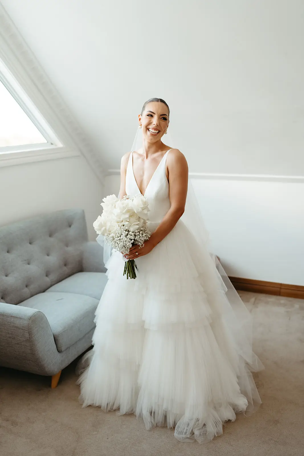 The bride with her bouquet in the light of the getting-ready loft, Maleny Manor