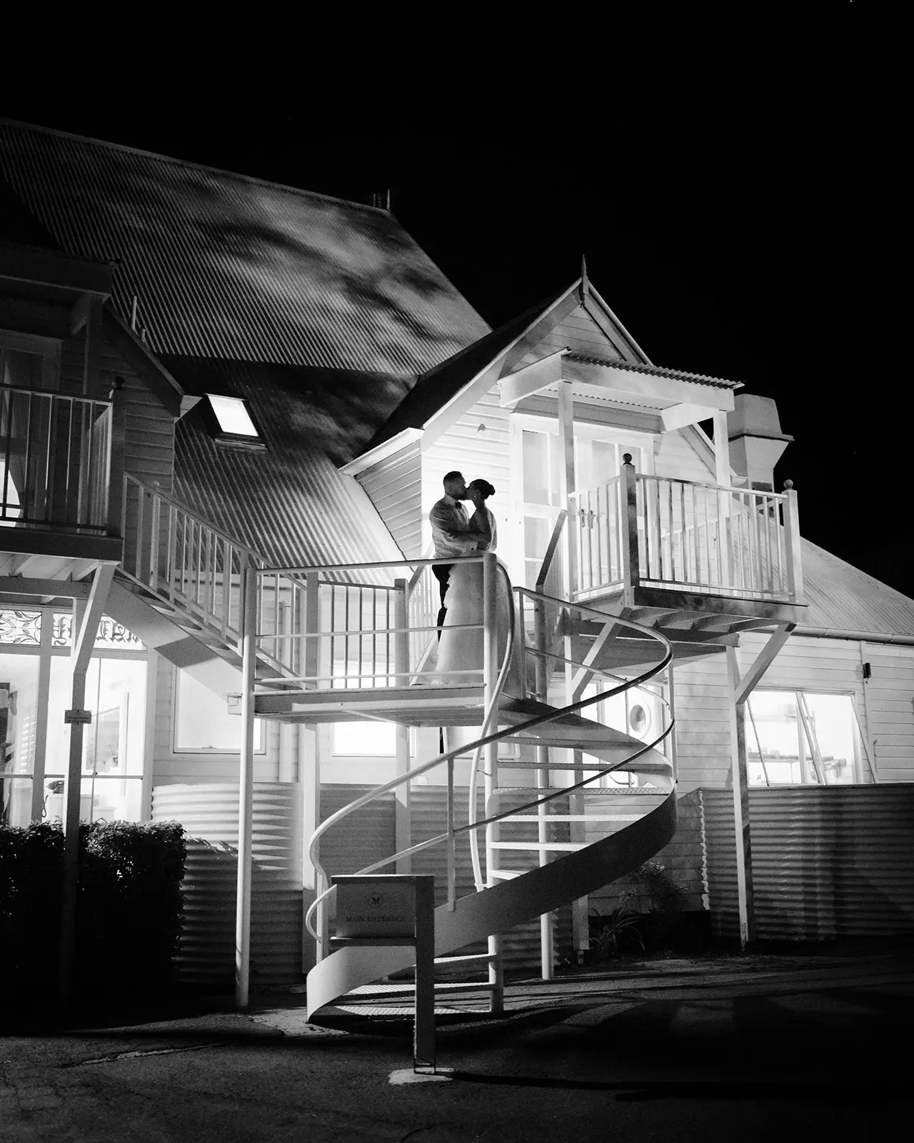 Black and white — the manor and its curved stair lit at night, Maleny Manor