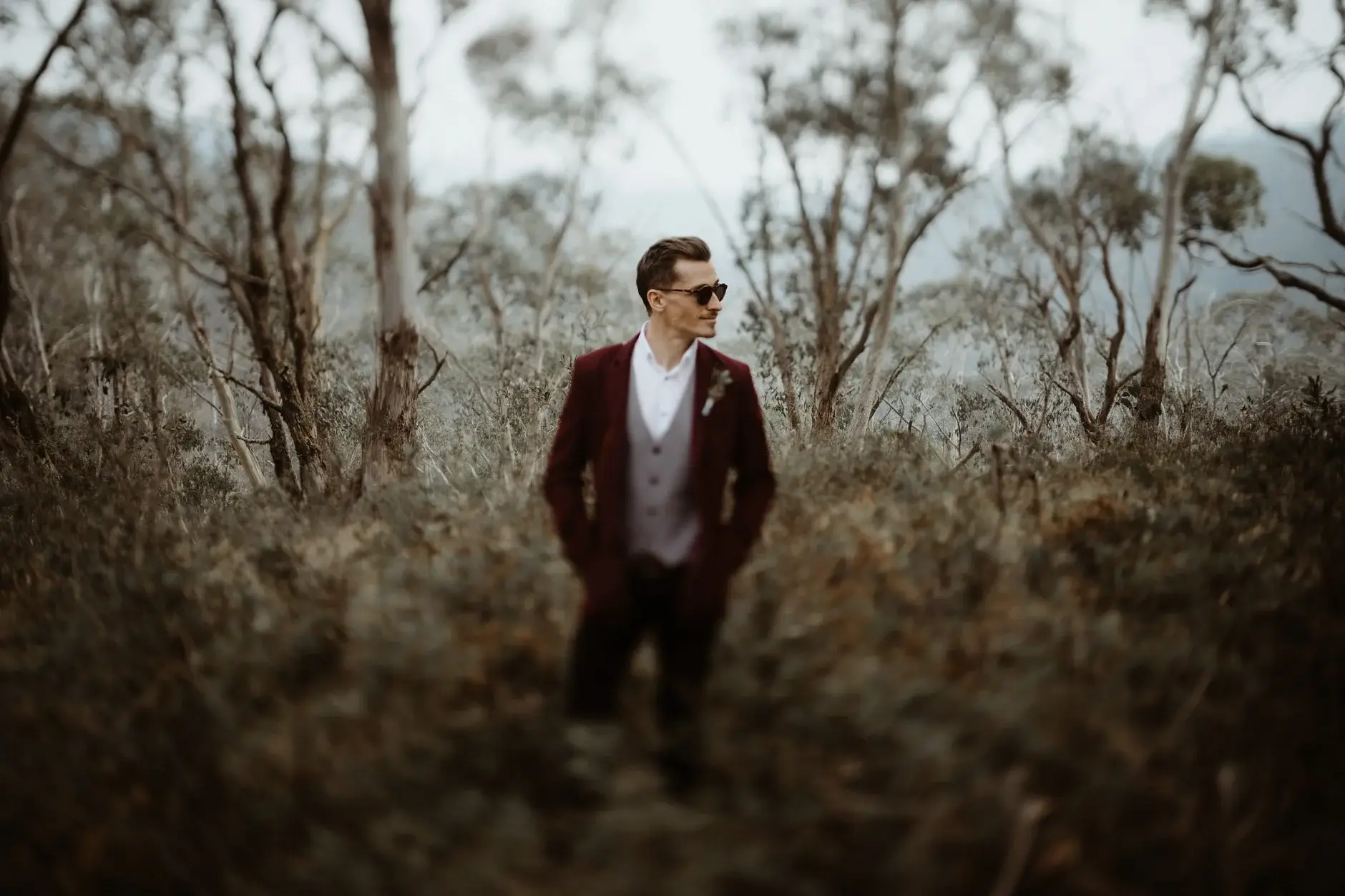 Drew in sunglasses walking through the burnt scrub, New England