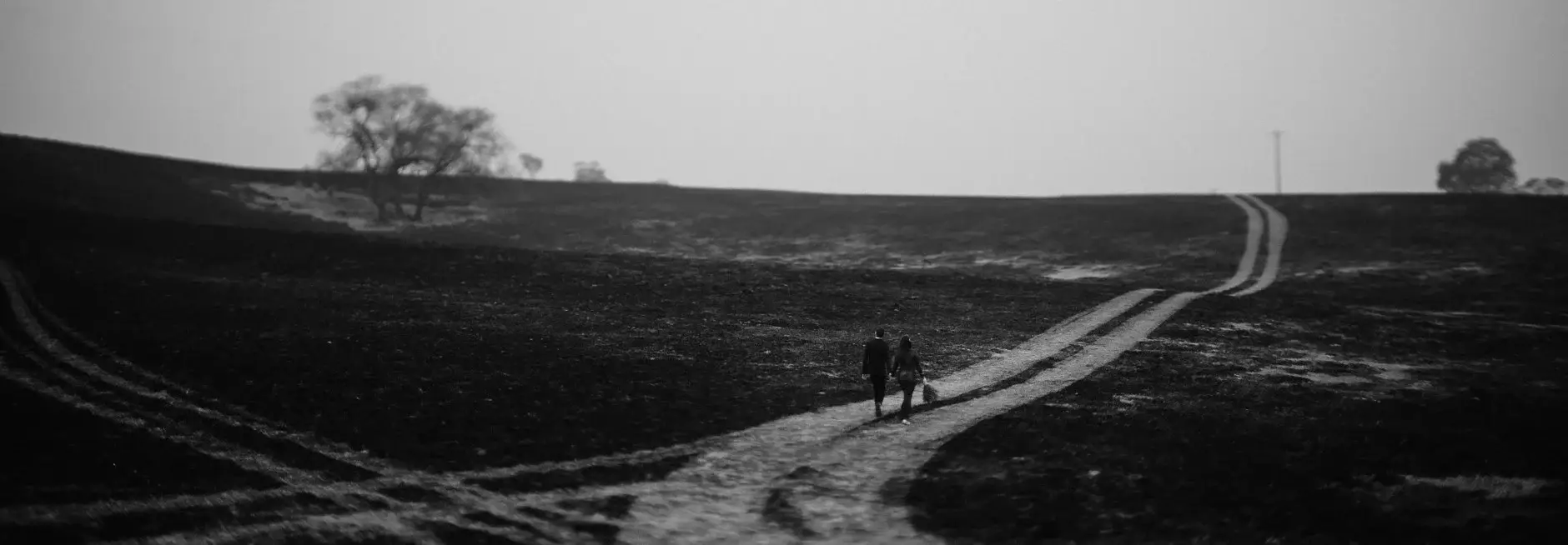The two of them tiny on a burnt hillside track, black and white