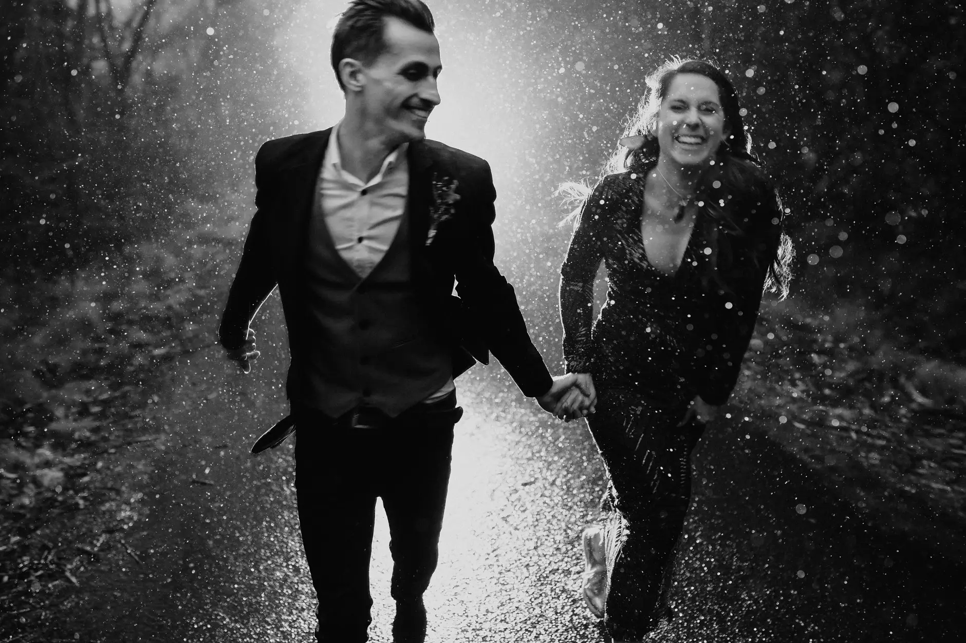 Laughing as they run through the downpour, black and white, New England
