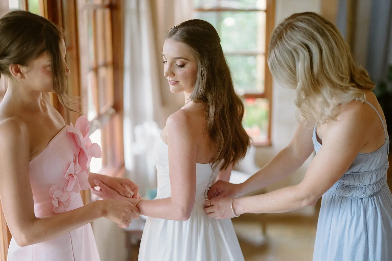 Bridesmaids doing up the back of the gown by the window, Nutting Hill Villa