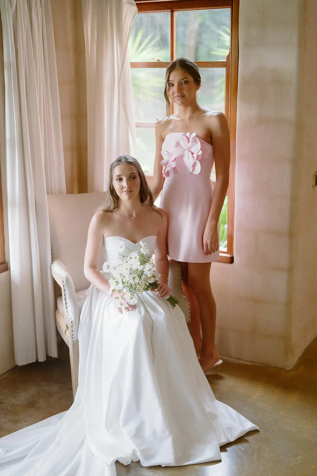 The bride in the doorway of the villa bedroom holding her bouquet, Nutting Hill Villa