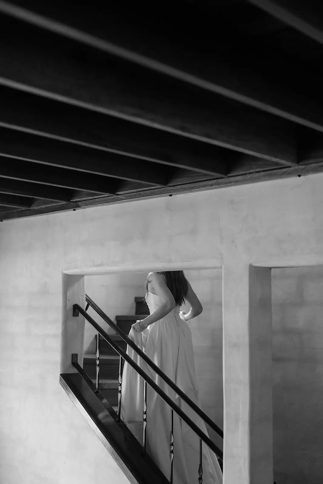 Black and white — coming down the villa staircase beneath the timber beams, Nutting Hill Villa