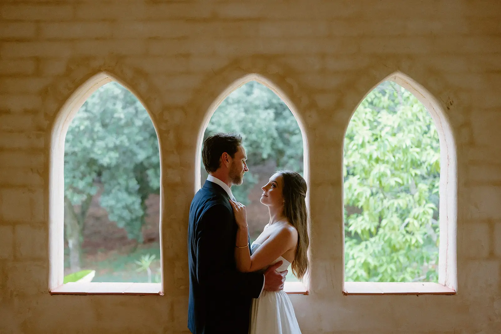The couple between three arched windows in the stone-walled room, Nutting Hill Villa