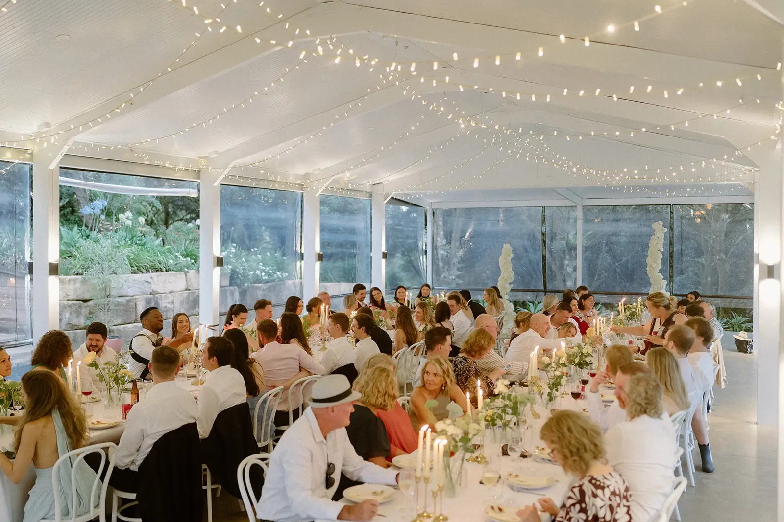 Long tables under the fairy-lit pavilion ceiling with the garden beyond, Nutting Hill Villa
