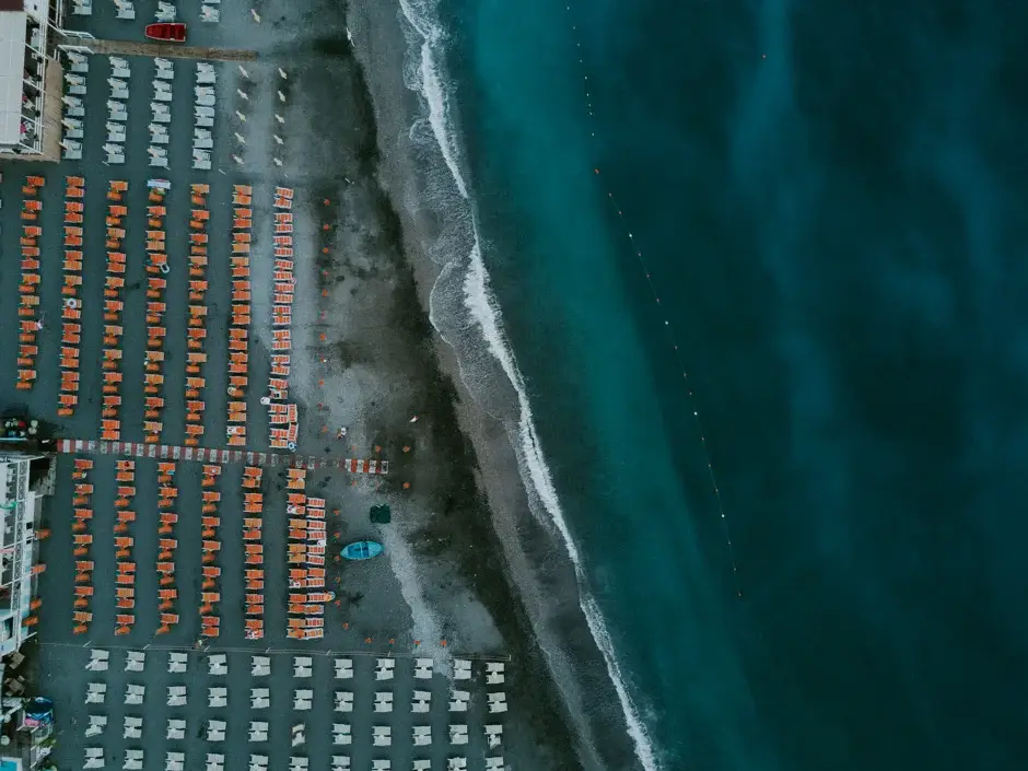 Rows of striped umbrellas on the sand seen from above, Amalfi Coast
