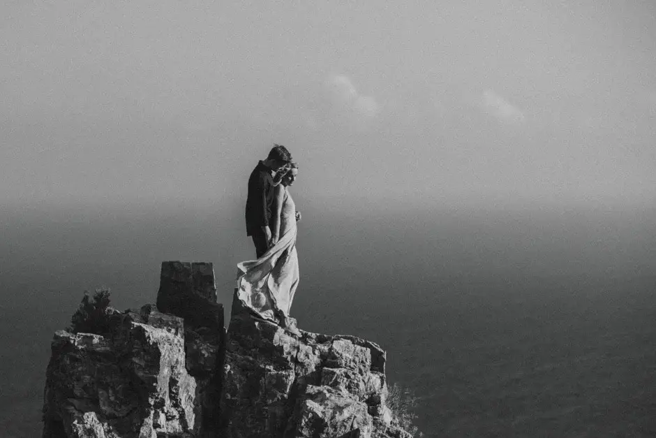 Emilie standing on a rock above the misty sea, black and white