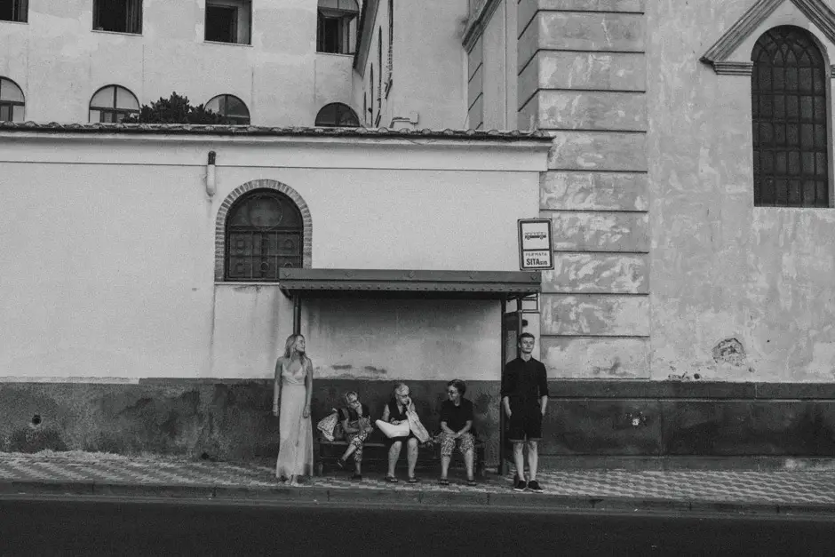 A white church wall with people sitting in its shade, black and white