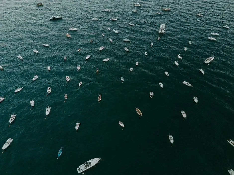 Small boats scattered across dark water seen from above