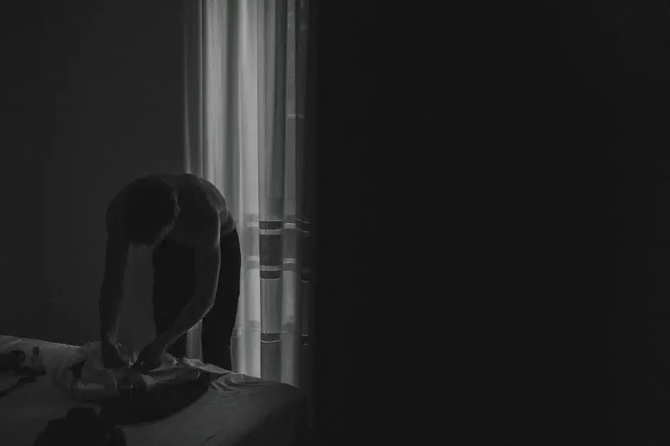 A dark interior with a chair by the window, black and white