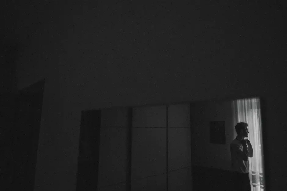 A figure at the far window in a dark room, black and white