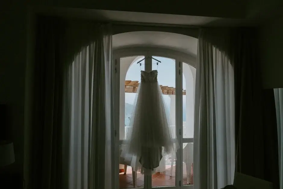 Emilie’s gown hanging in an arched window above the coast, Ravello