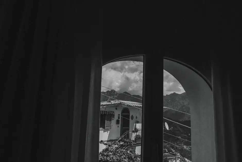 The view through curtained windows to the coast, black and white