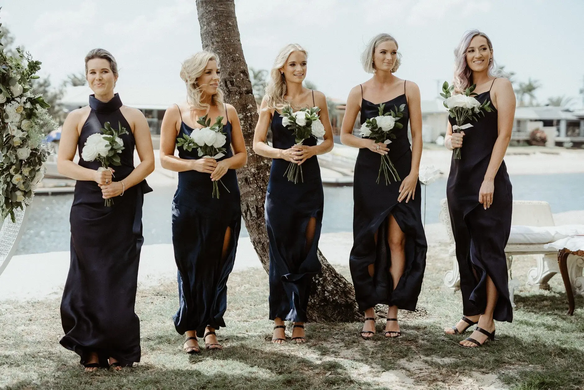 The bridesmaids standing with their bouquets by the water
