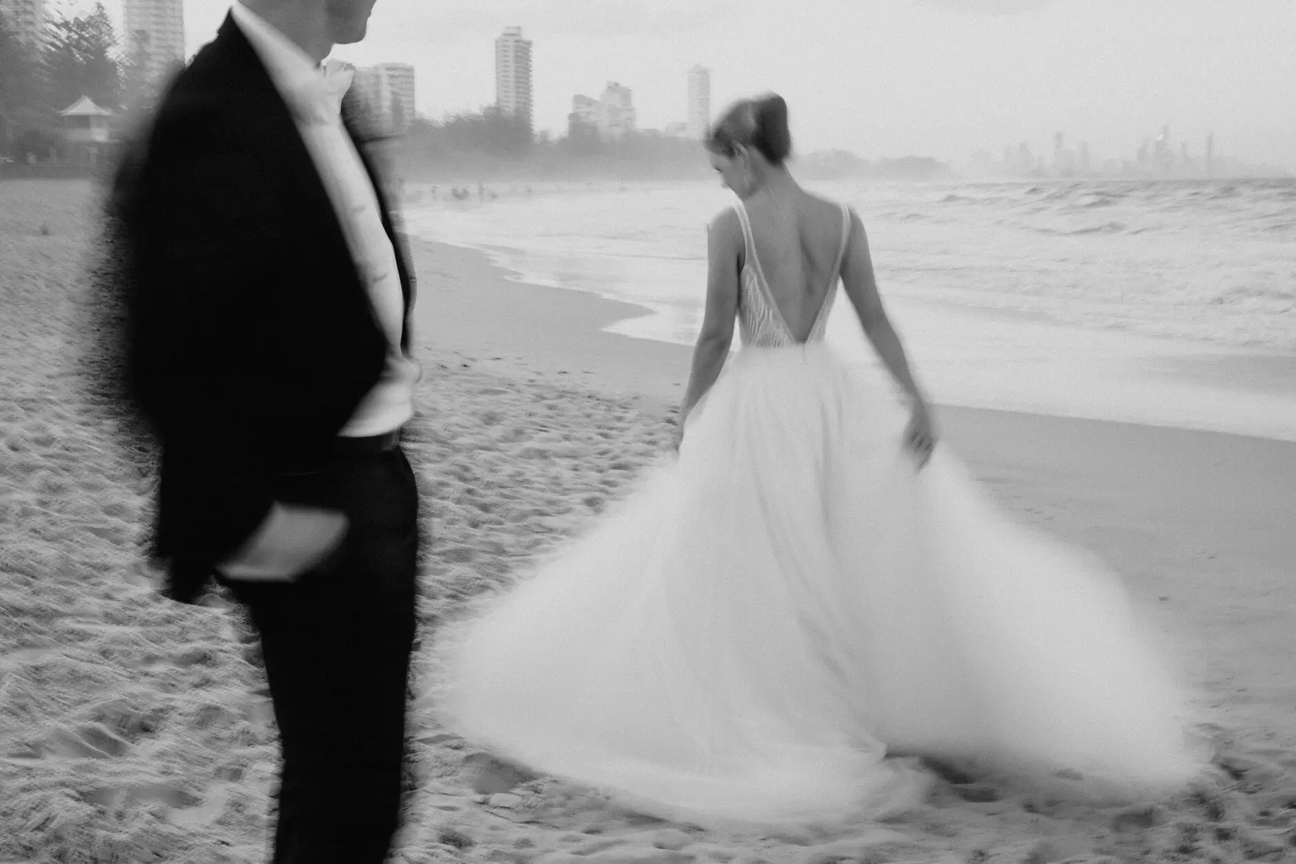 Clair and James walking the sand with the skyline behind