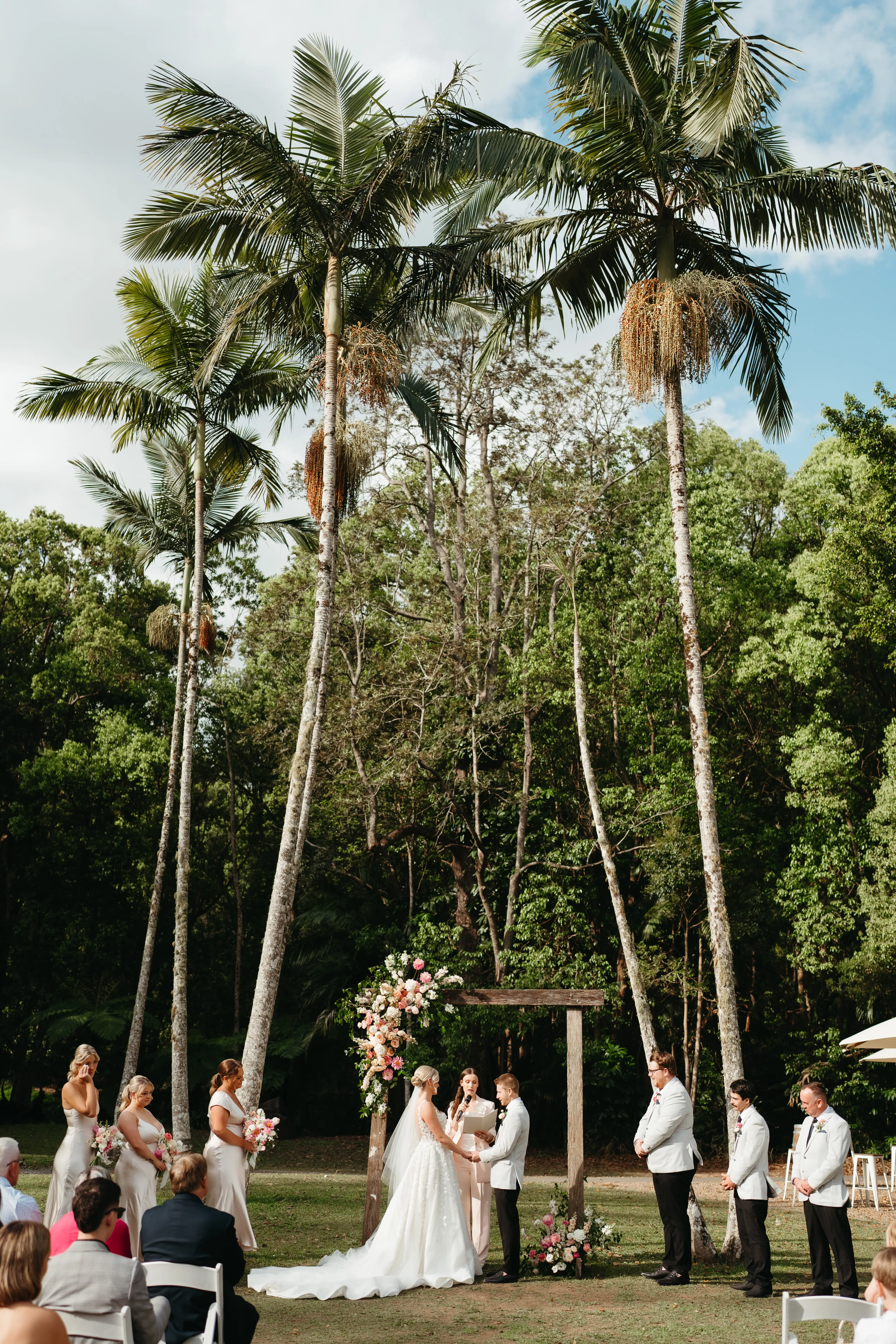 Vows at the timber arbour beneath the towering palms on the Ceremony Lawn, The Acre Boomerang Hills