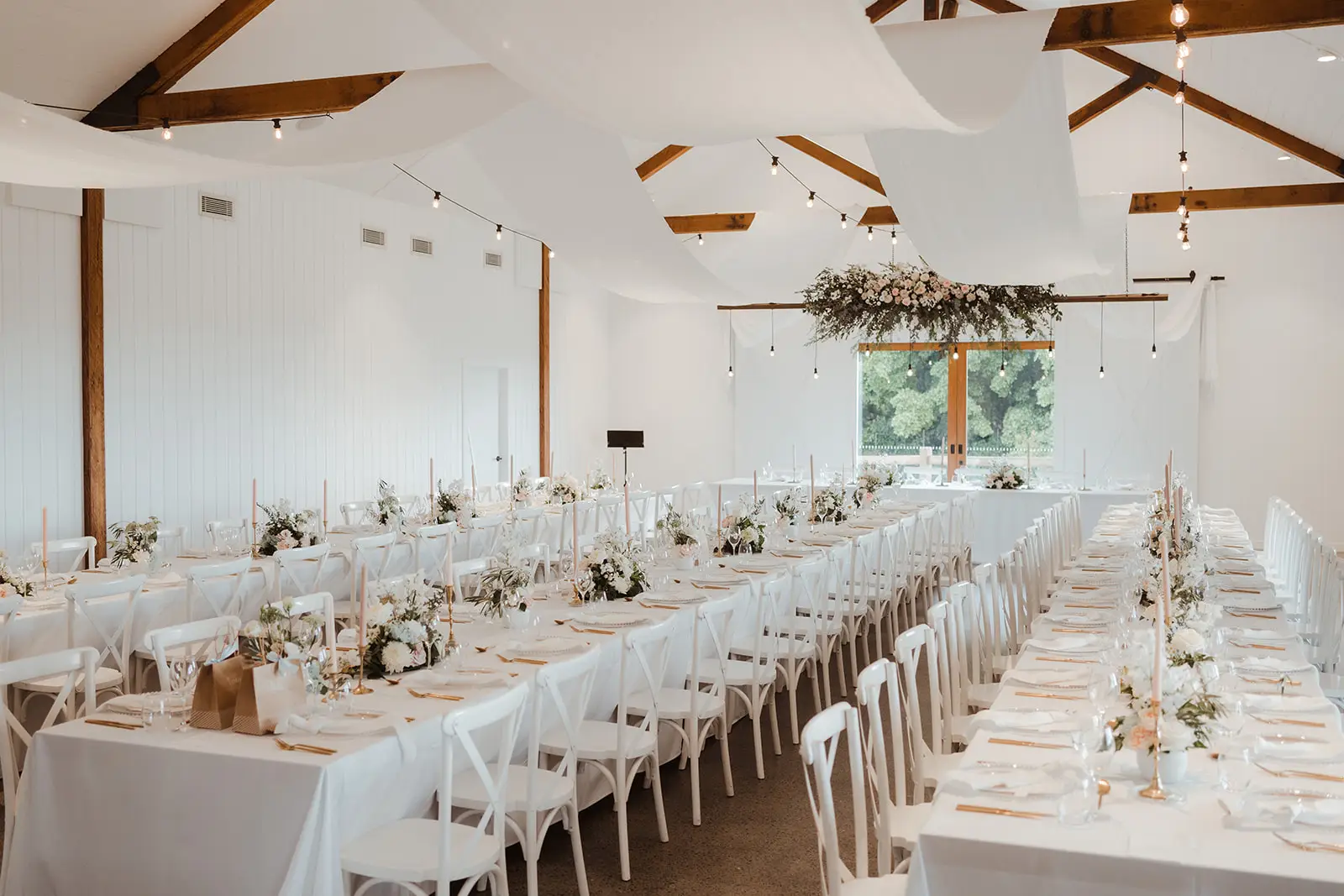 The barn set for dinner — white linen, timber trusses and long tables, Summergrove Estate