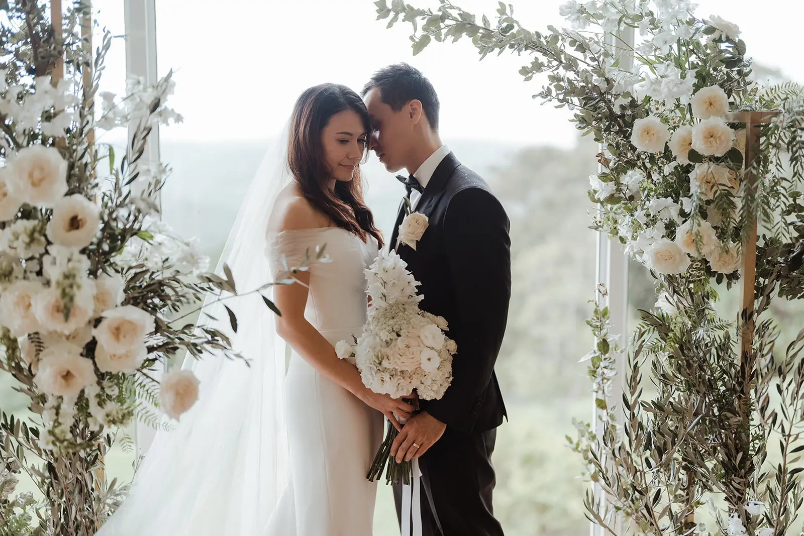 The couple at the floral arch with the hinterland behind, Summergrove Estate