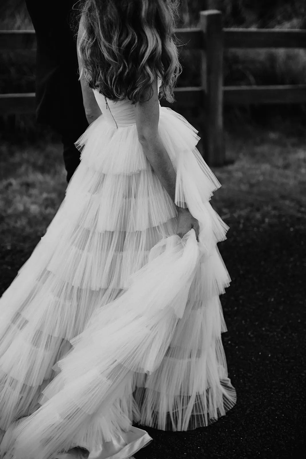 Black and white — the tiered tulle skirt swinging as she turns by the fence, Summergrove Estate
