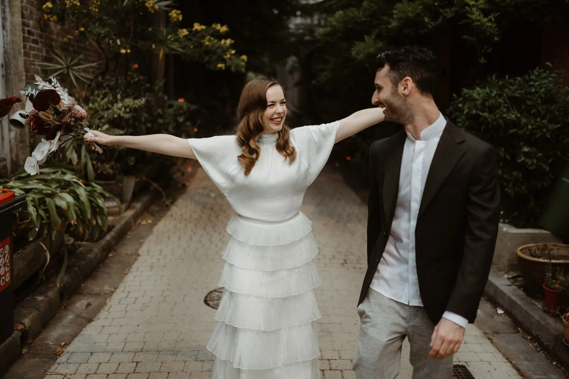 Sophie with her arms flung wide, laughing with Jonathan in the laneway, Surry Hills