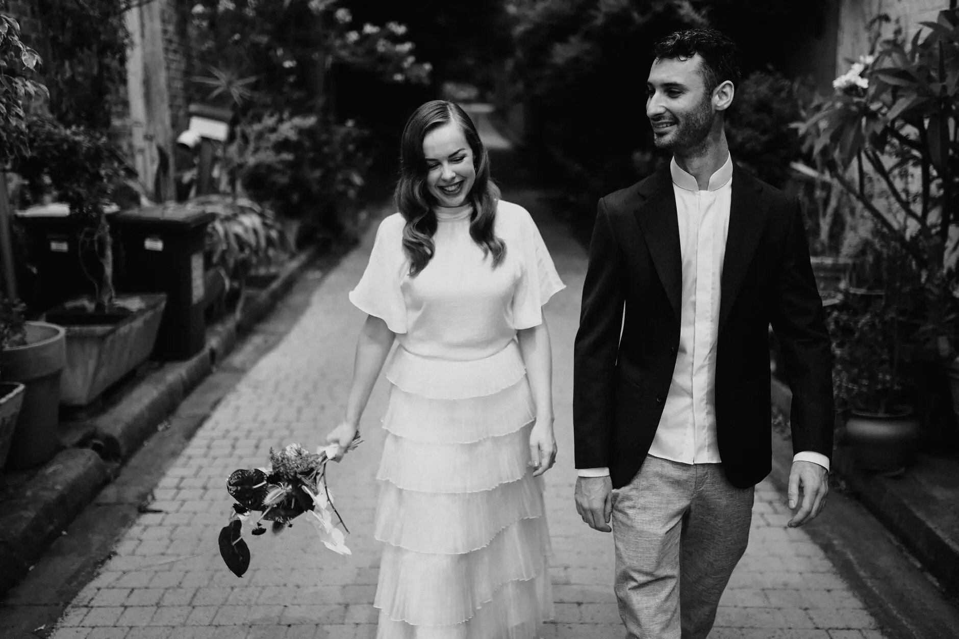 Sophie and Jonathan walking hand in hand down the lane, in black and white, Surry Hills