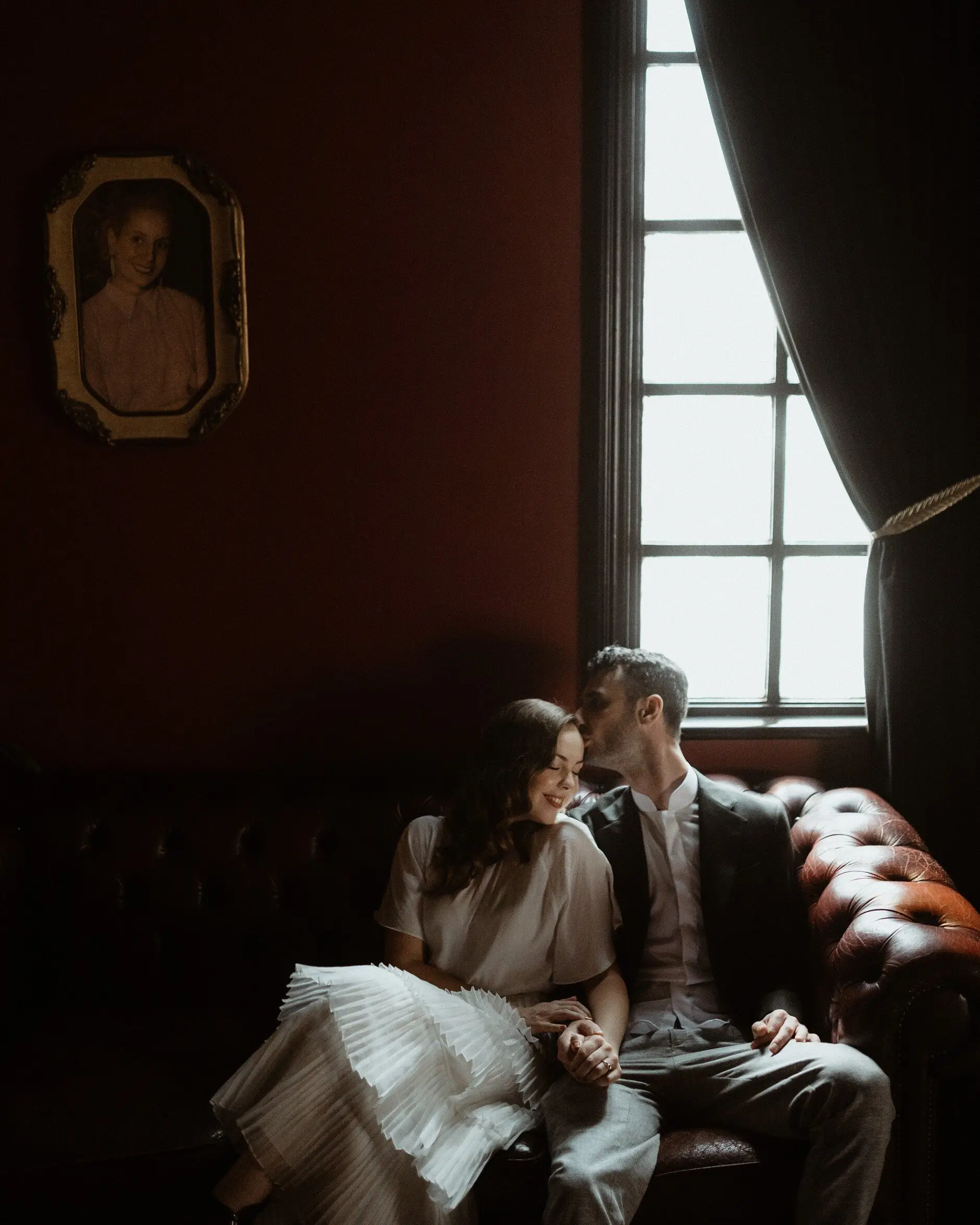 The red room upstairs at Casa with its framed portrait and leather chesterfield, Surry Hills