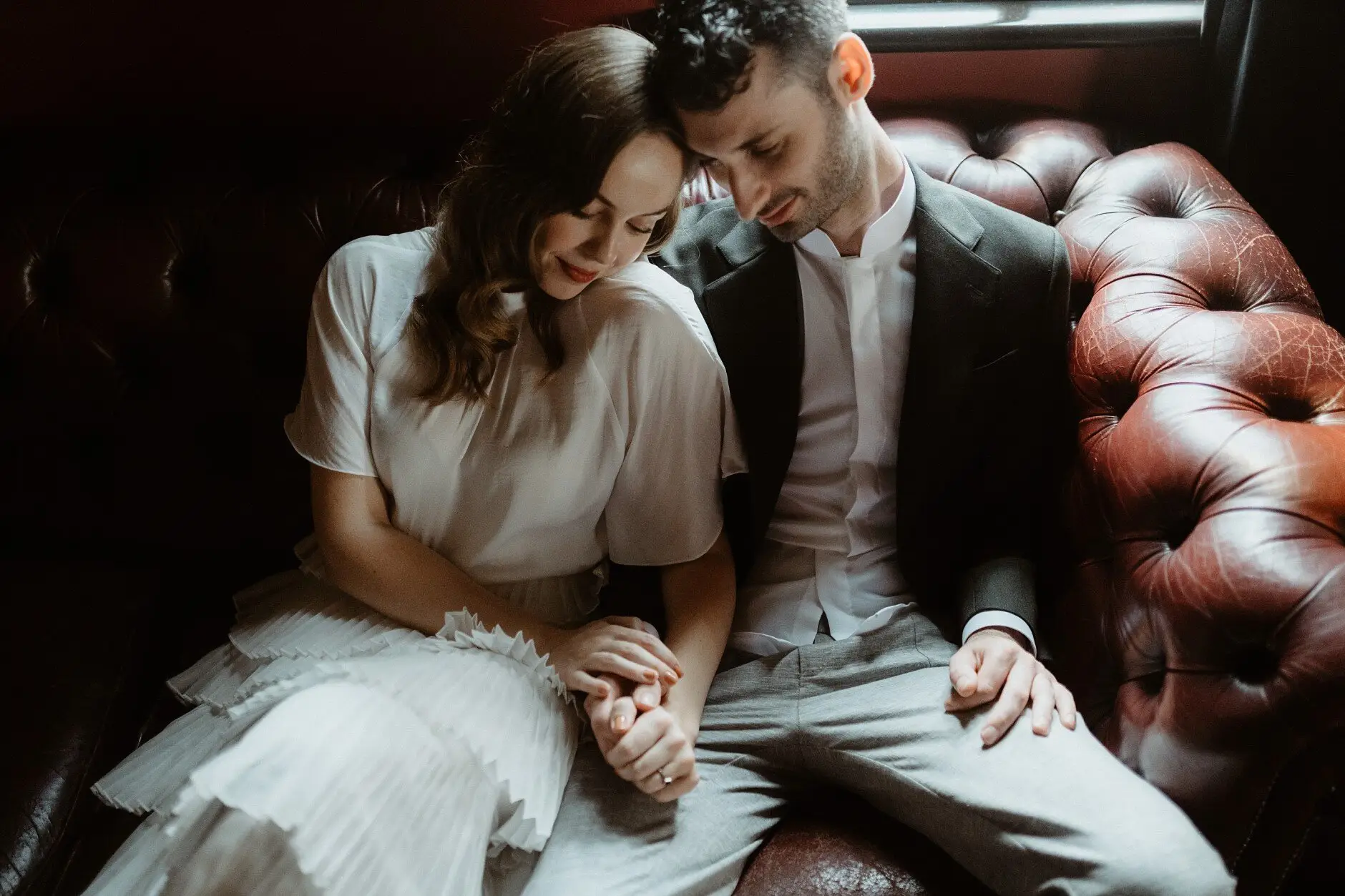 Sophie and Jonathan sitting close on the chesterfield, hands together, Casa, Surry Hills