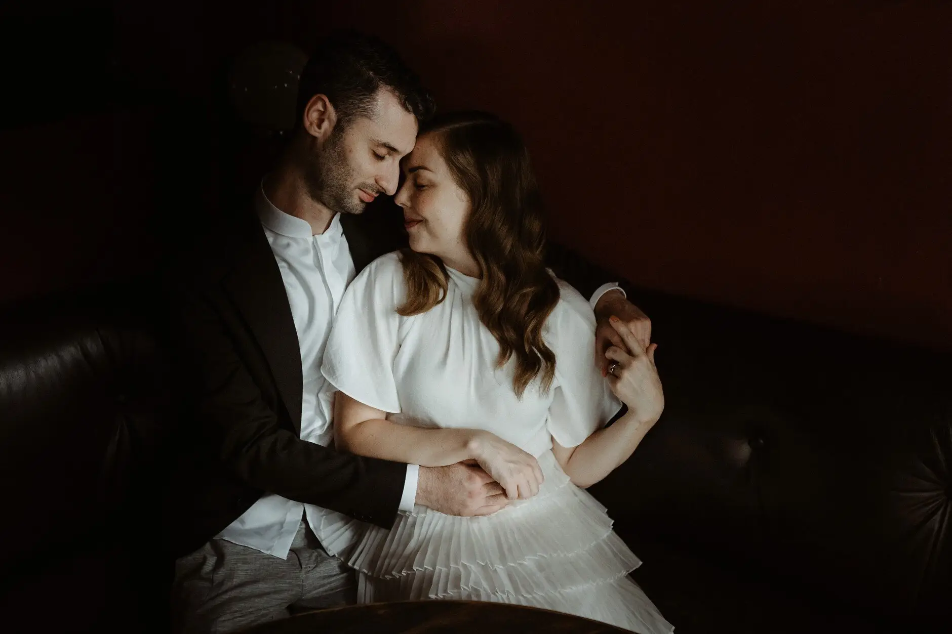 The two of them holding each other on the banquette in the red room, Casa, Surry Hills