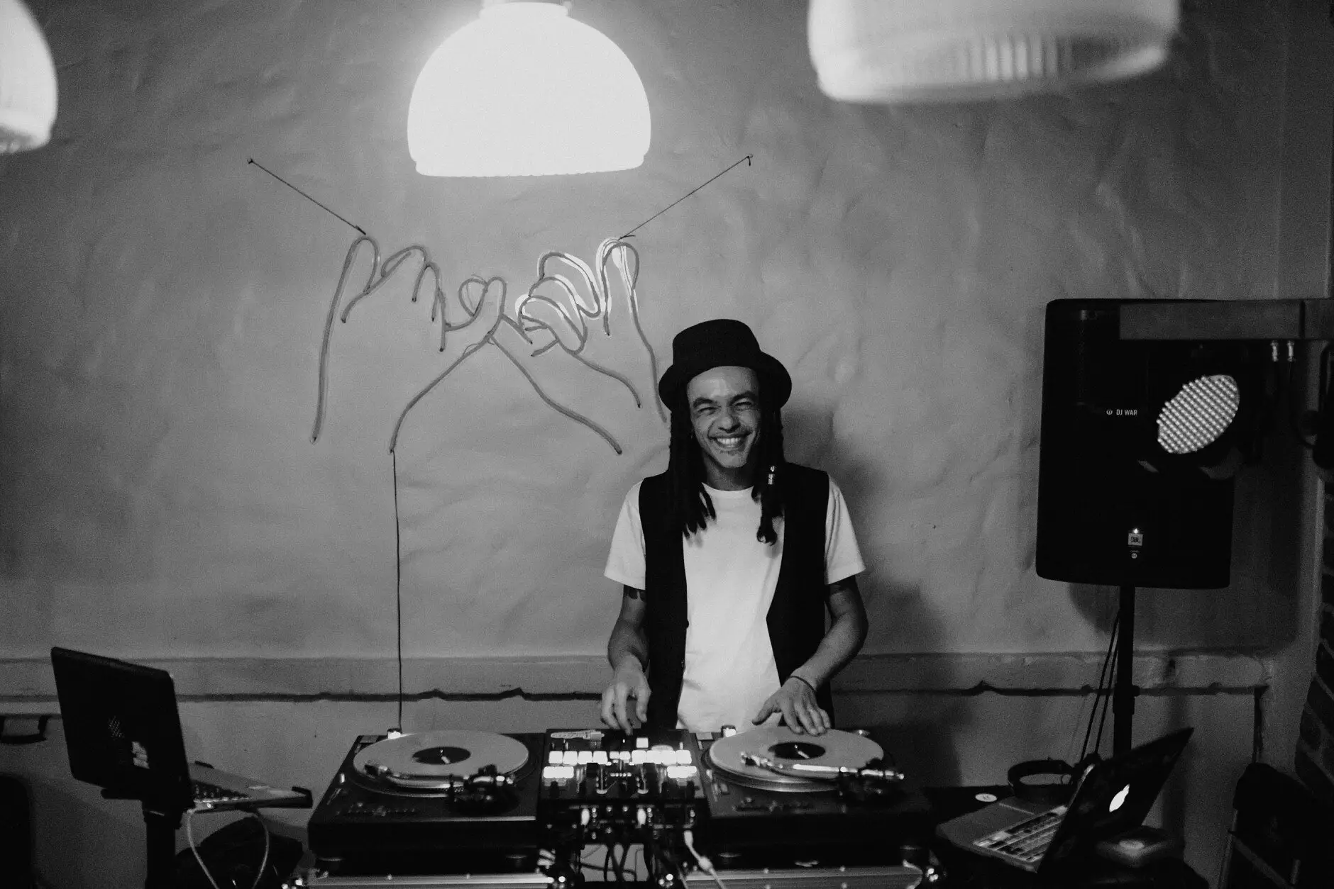 The DJ behind the decks beneath the wire sign, in black and white, Porteño, Surry Hills