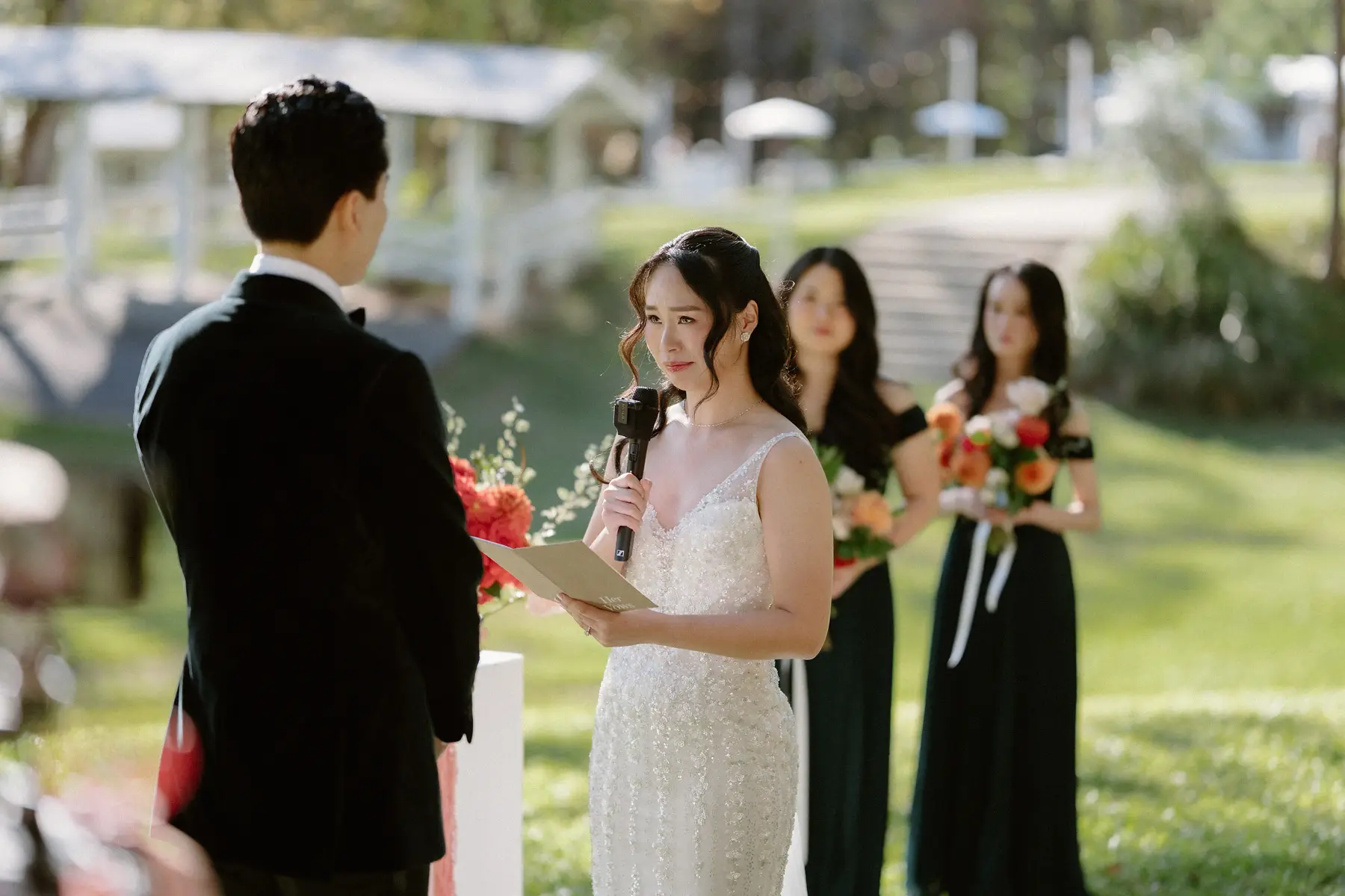 Cathy reading her vows into the microphone with her bridesmaids behind her, Tall Trees Tallebudgera Valley