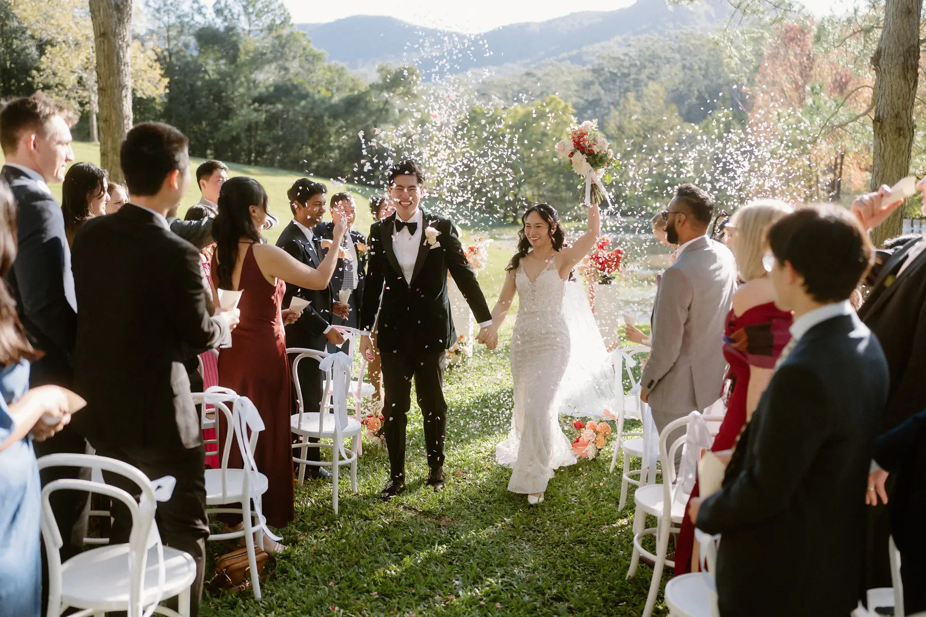 Cathy holding her bouquet up as they come back through the confetti, Tall Trees Tallebudgera Valley