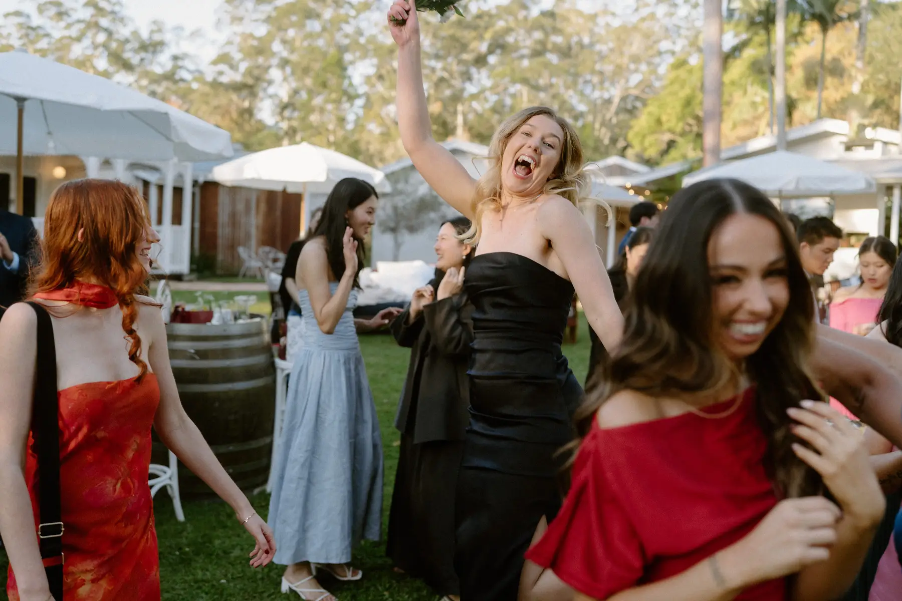 Guests laughing and grabbing each other after the bouquet toss, Tall Trees Tallebudgera Valley