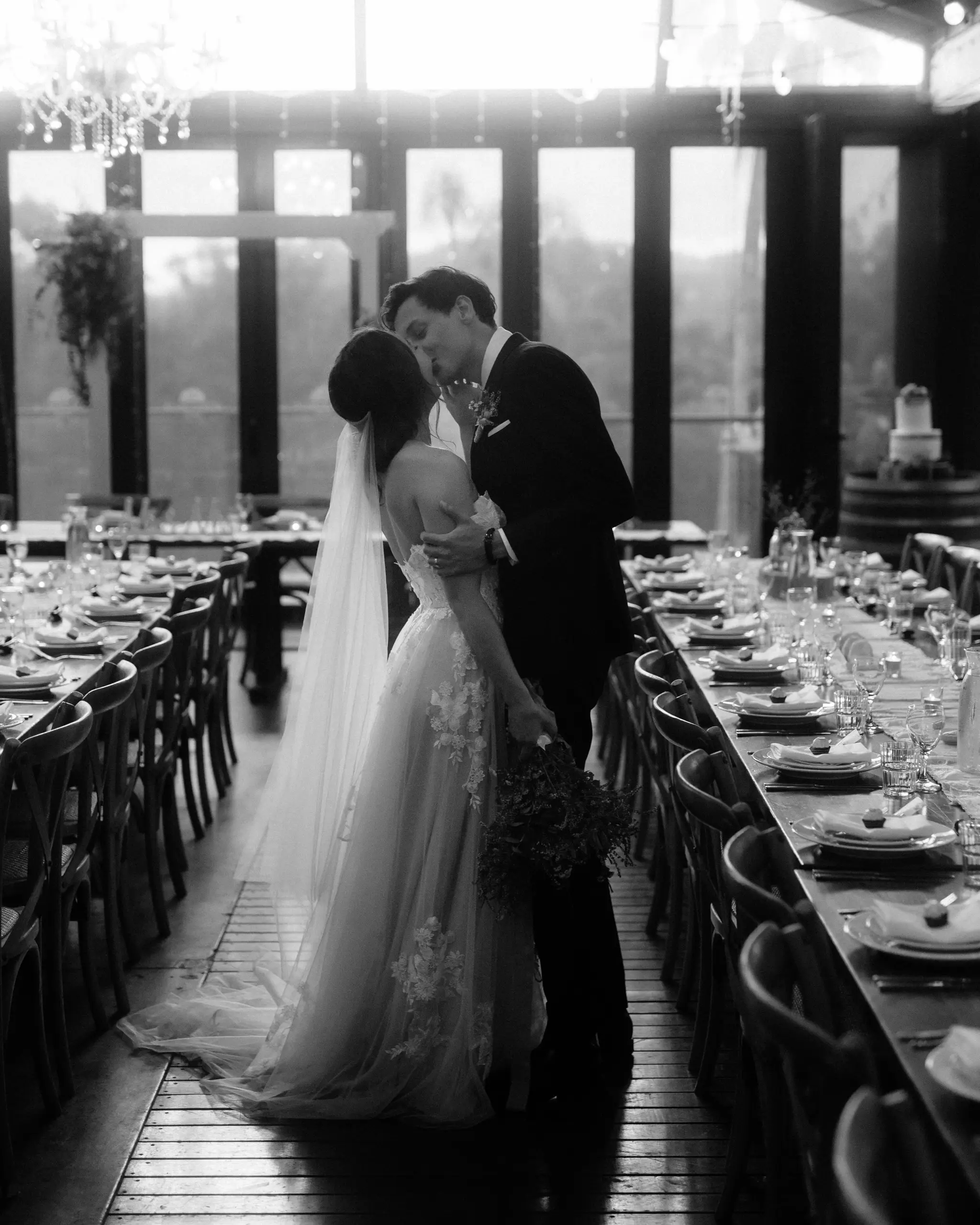 Couple kissing beside a long reception table