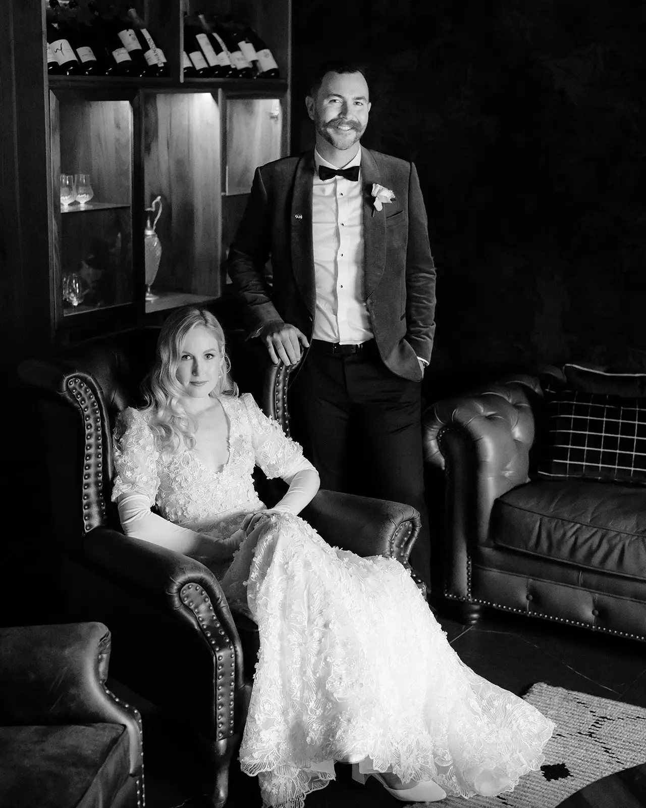 Black and white portrait of the couple on a leather Chesterfield in the Gentleman's Retreat, The Valley Estate