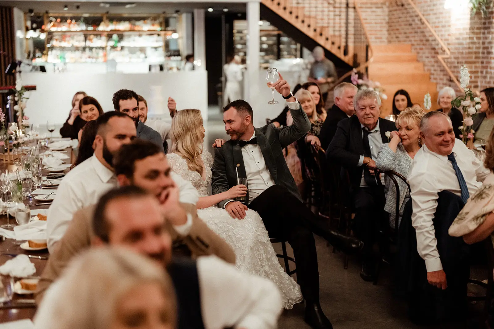 Guests laughing at the tables during speeches, the pale columns of the room behind, The Valley Estate