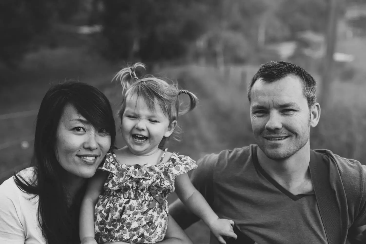Black and white photo of Van with his wife and their laughing daughter in pigtails