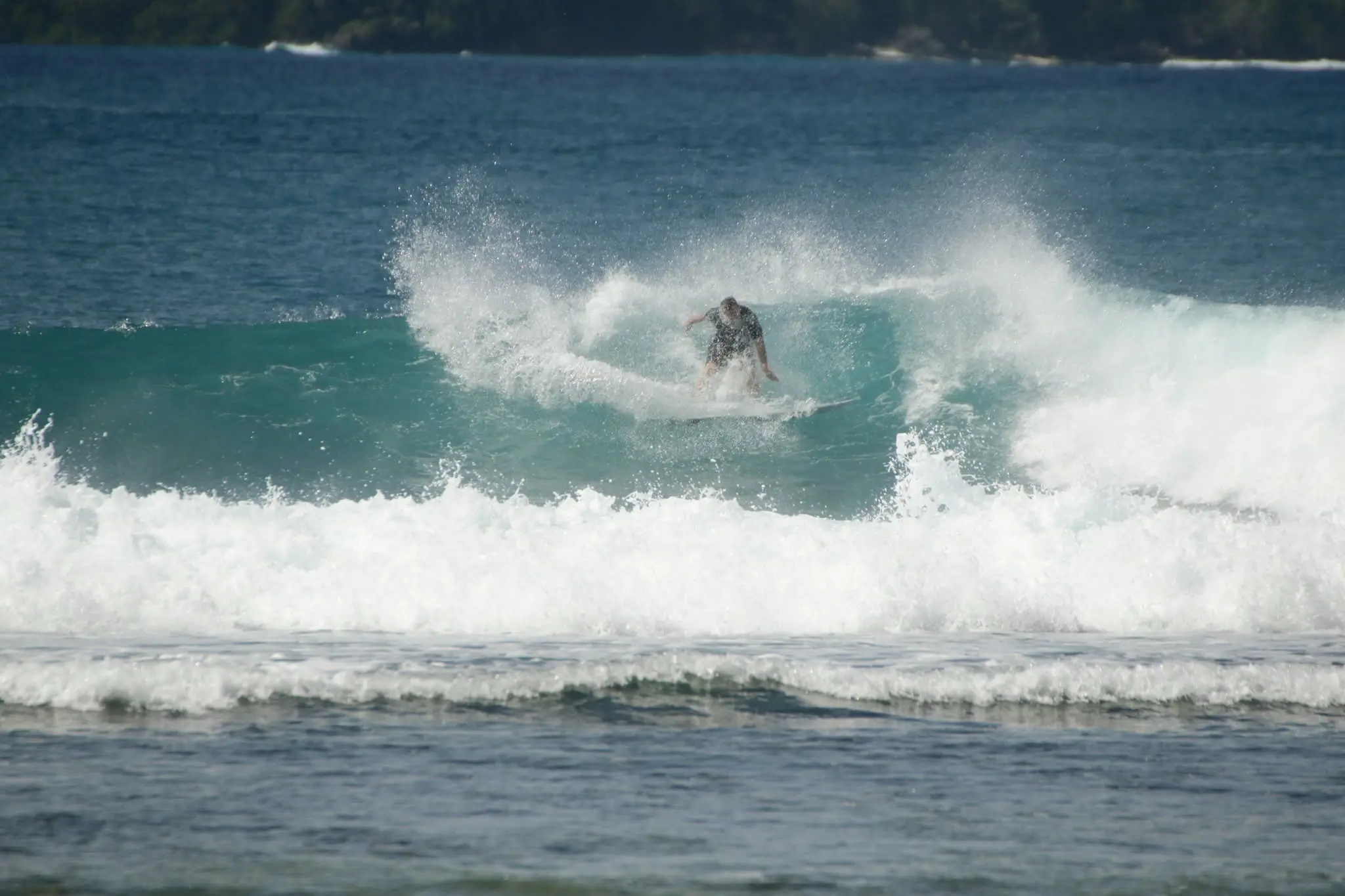 Van surfing, throwing spray off the top of a turquoise wave
